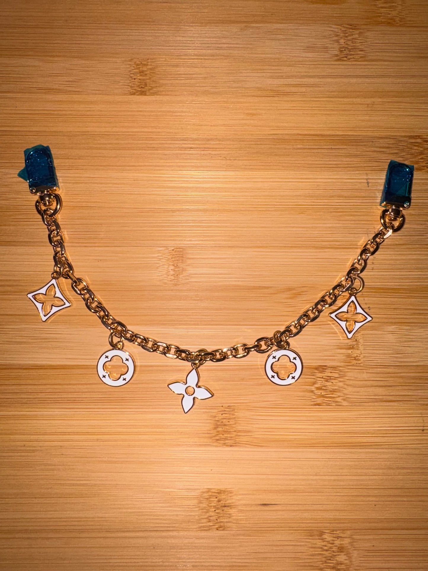 White and gold “LV” purse charm.