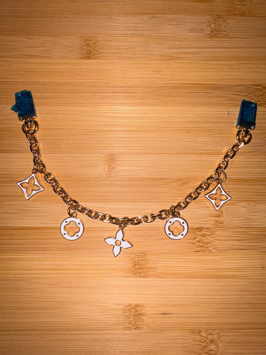 White and gold “LV” purse charm.